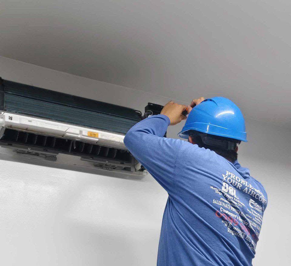 Jakintech technician servicing a wall-mounted air conditioning unit